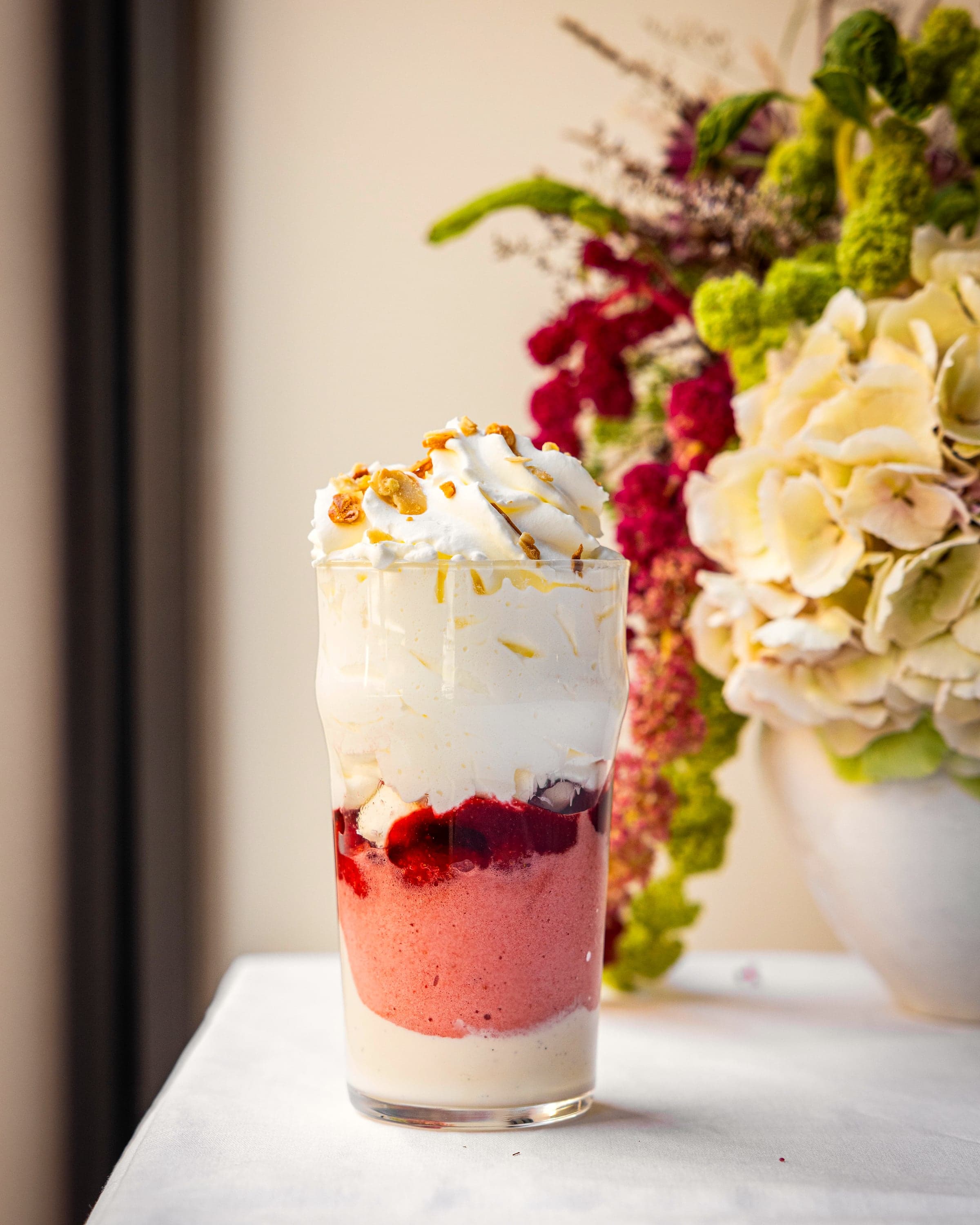 Verrine sucrée dressée près d’un bouquet de fleurs