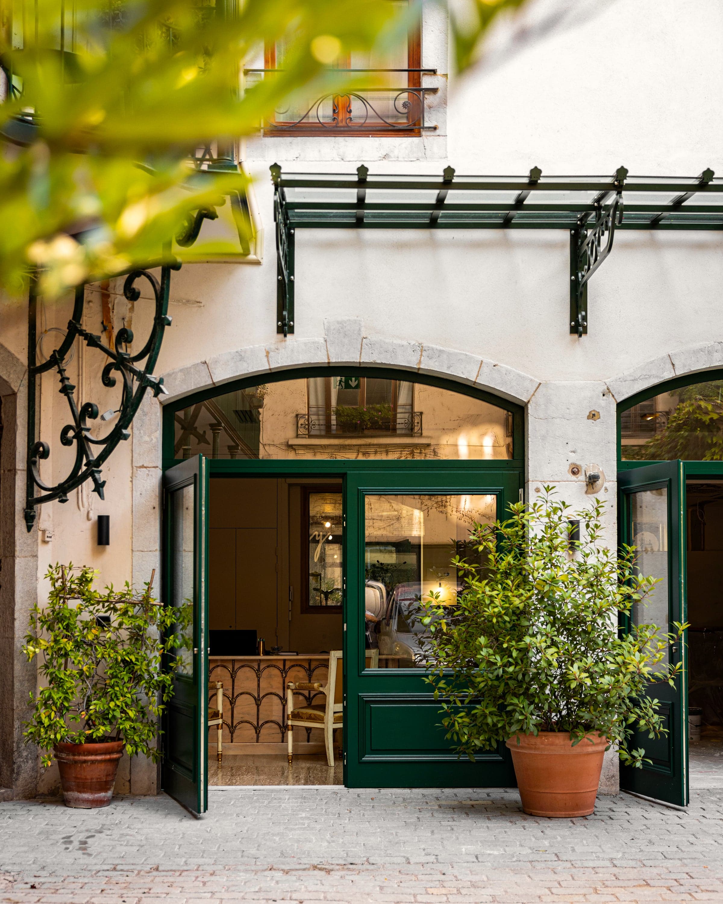 Façade de la brasserie, ferronneries vertes et plantes en pot