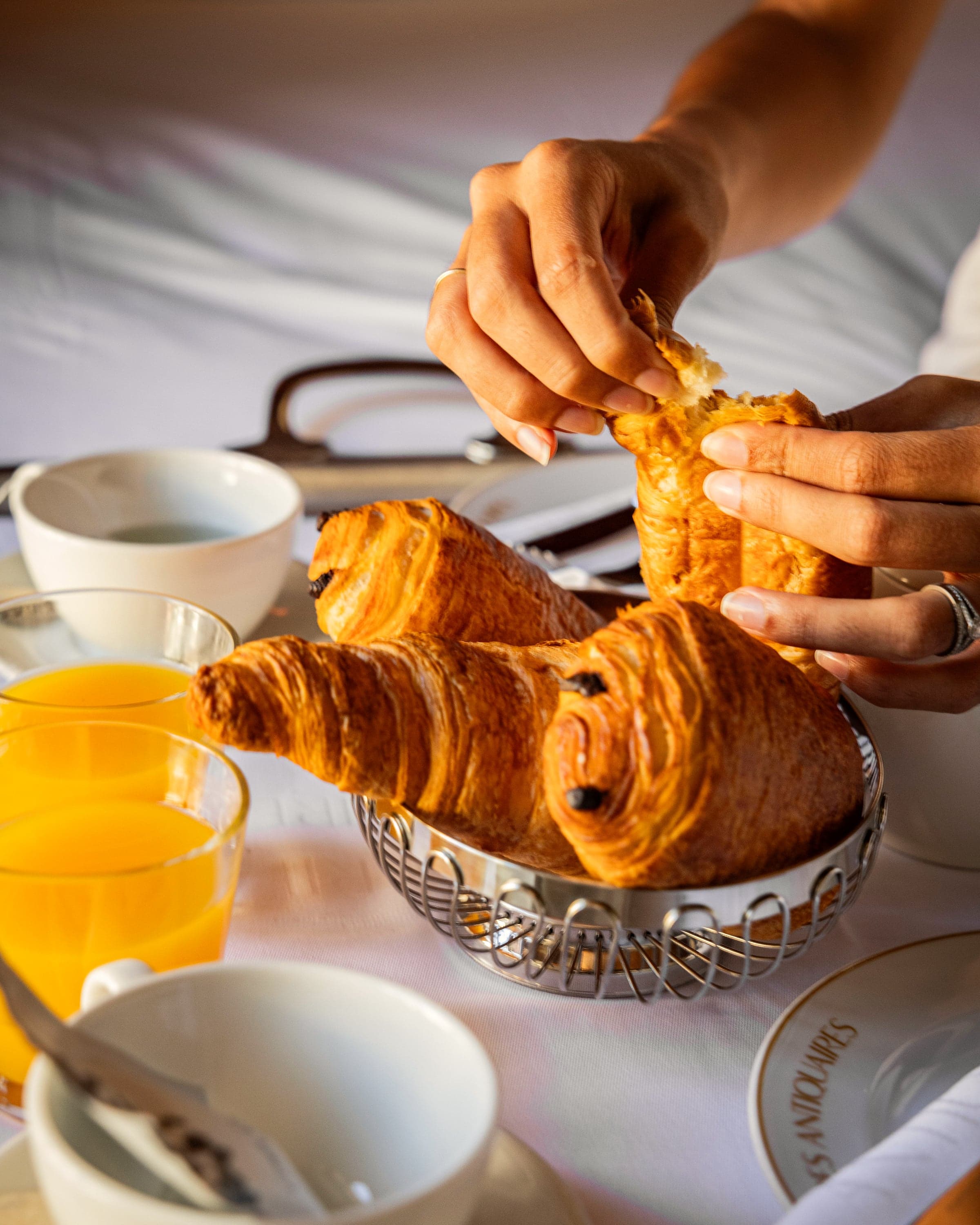Viennoiserie rompue à la main au-dessus d’une table de petit-déjeuner